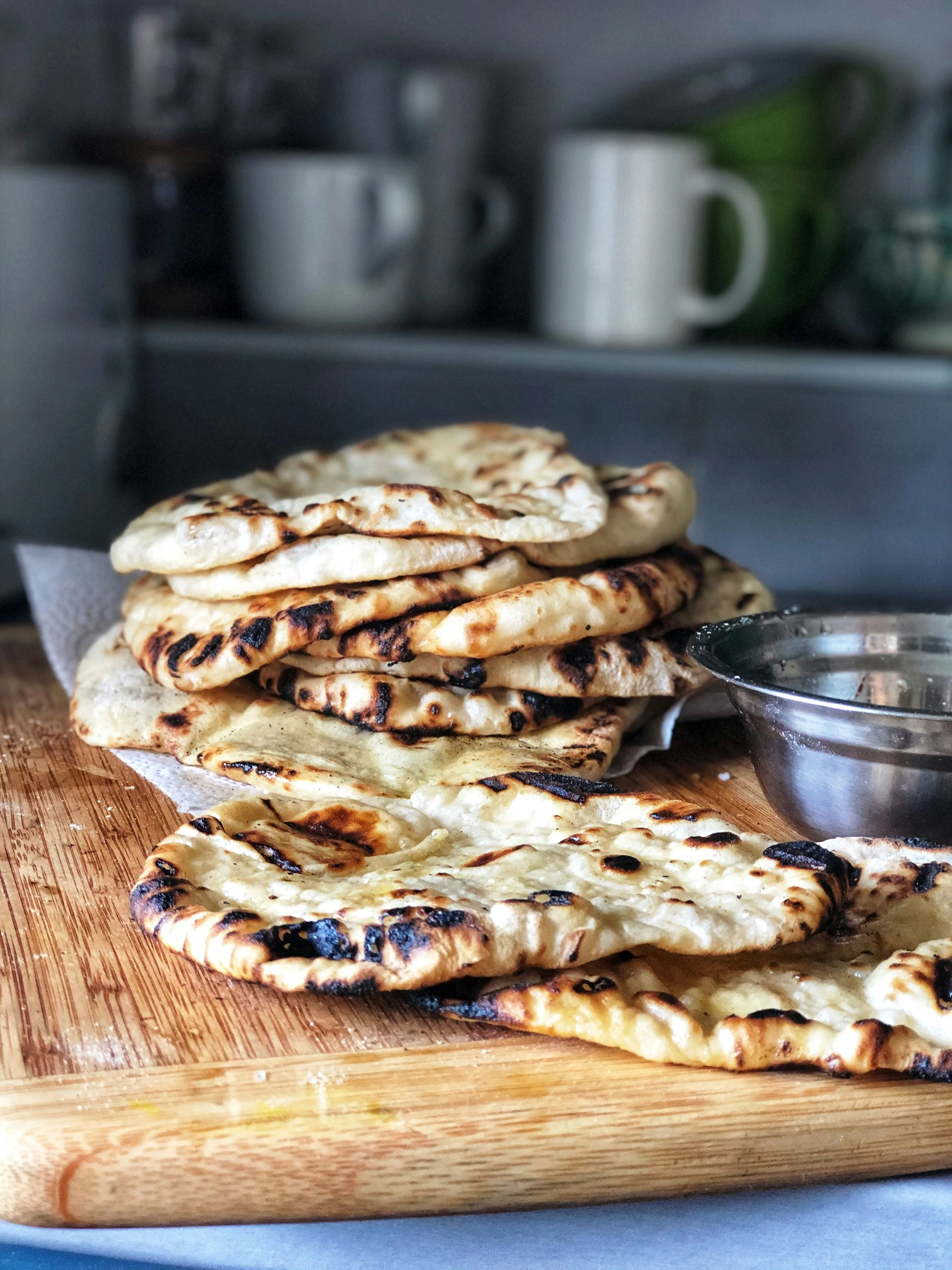 A pile of naan on top of a cutting board.