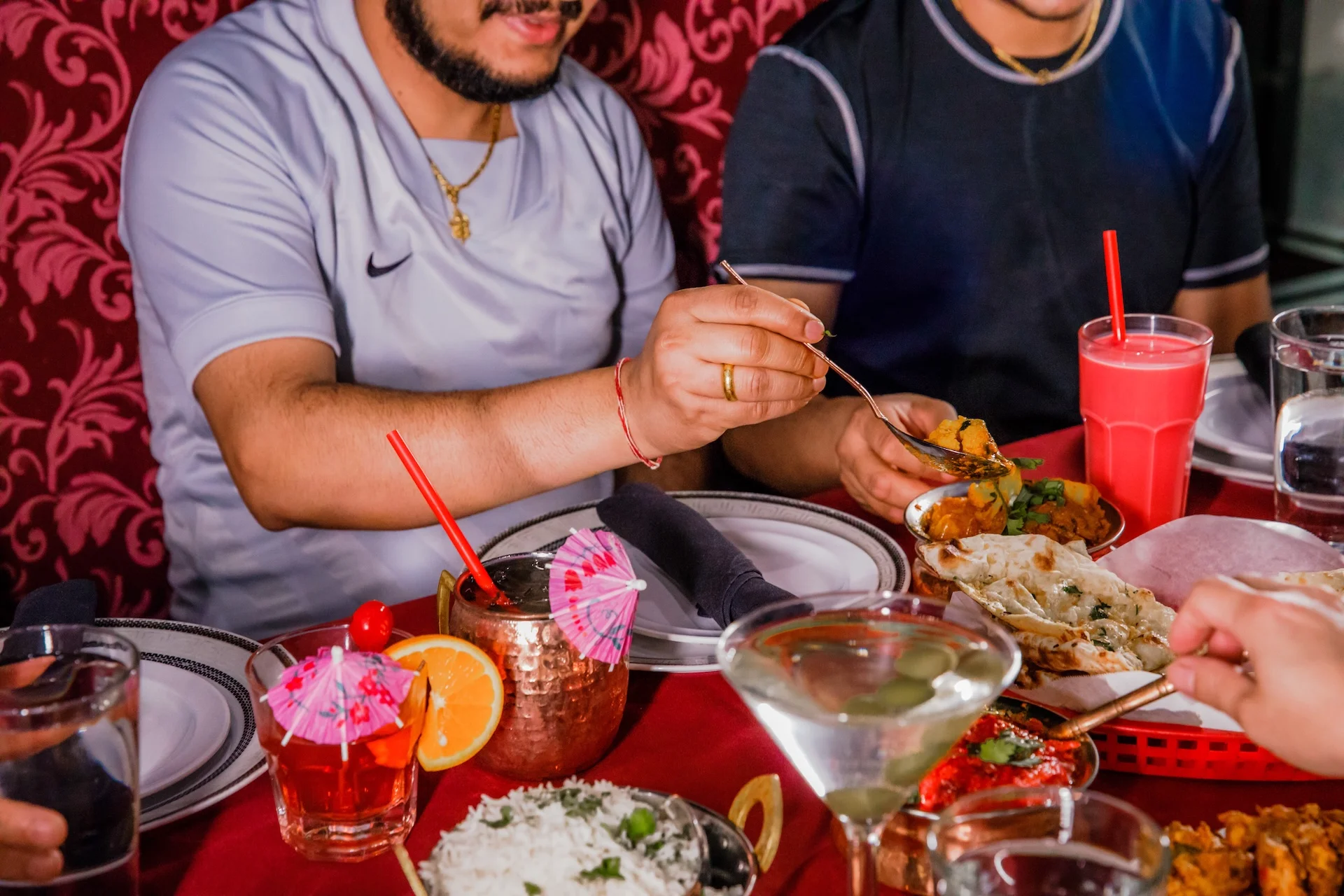 Guests enjoying a lively and exceptional dining experience at Mint Indian Restaurant, sharing a table filled with food and colorful cocktails.