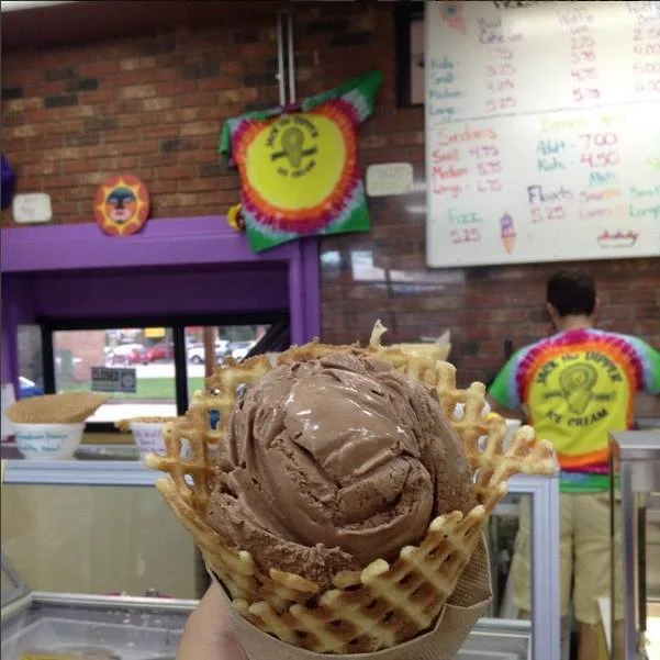 Chocolate ice cream in a waffle cone at a vibrant ice cream shop