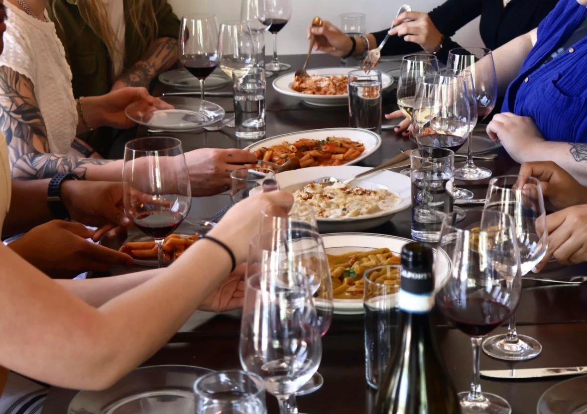 Group dining with Italian pasta dishes and red wine