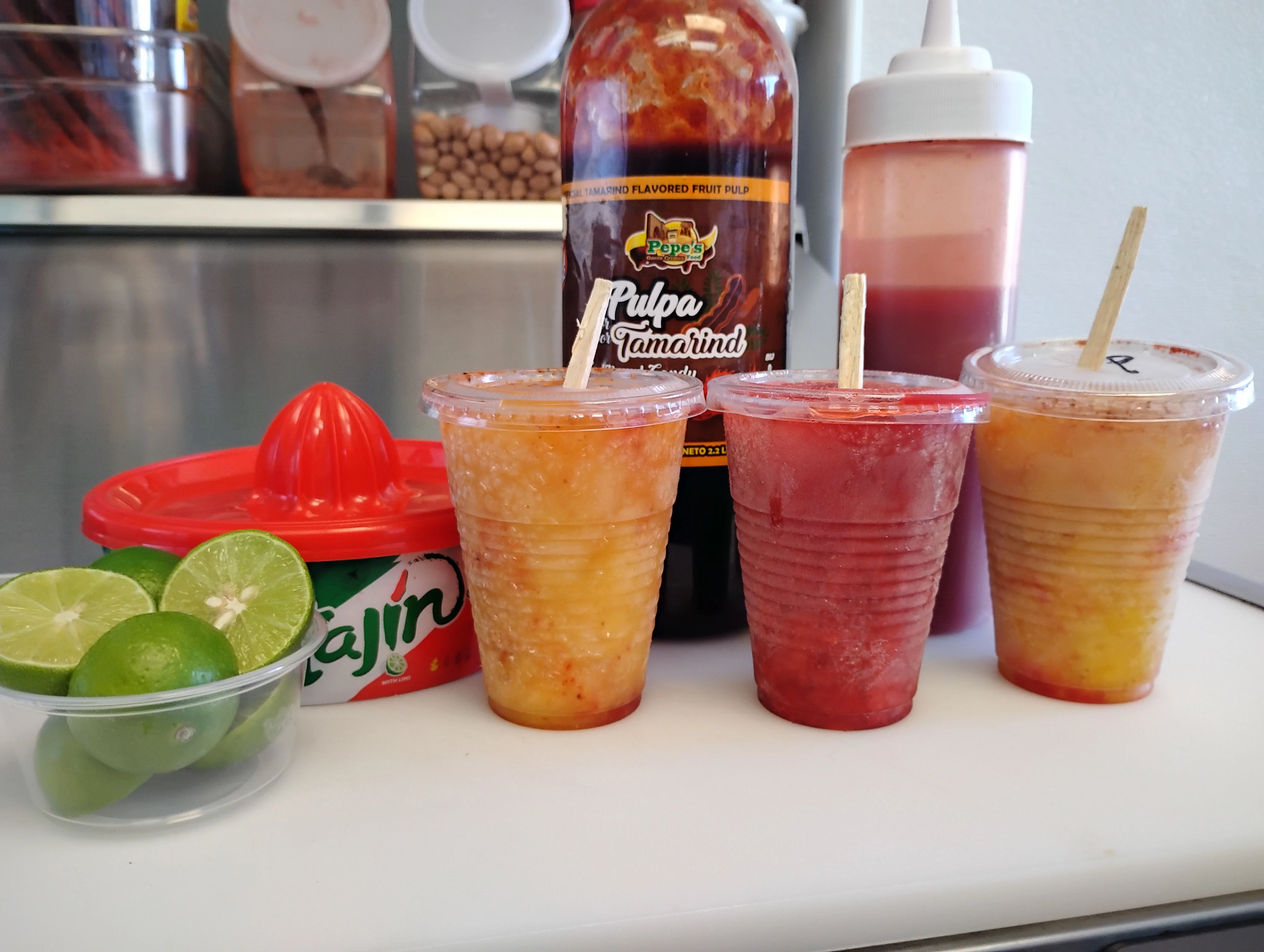 Colorful Mexican aguas frescas in clear cups with lime and Tajín
