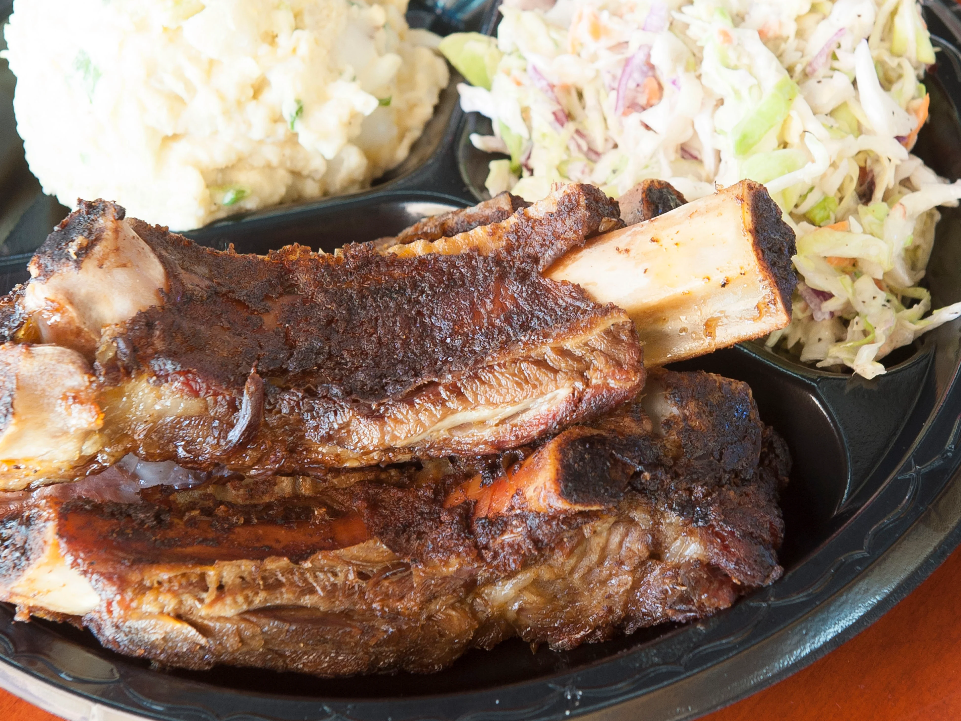 Southern-style beef ribs with sides of mashed potatoes and coleslaw