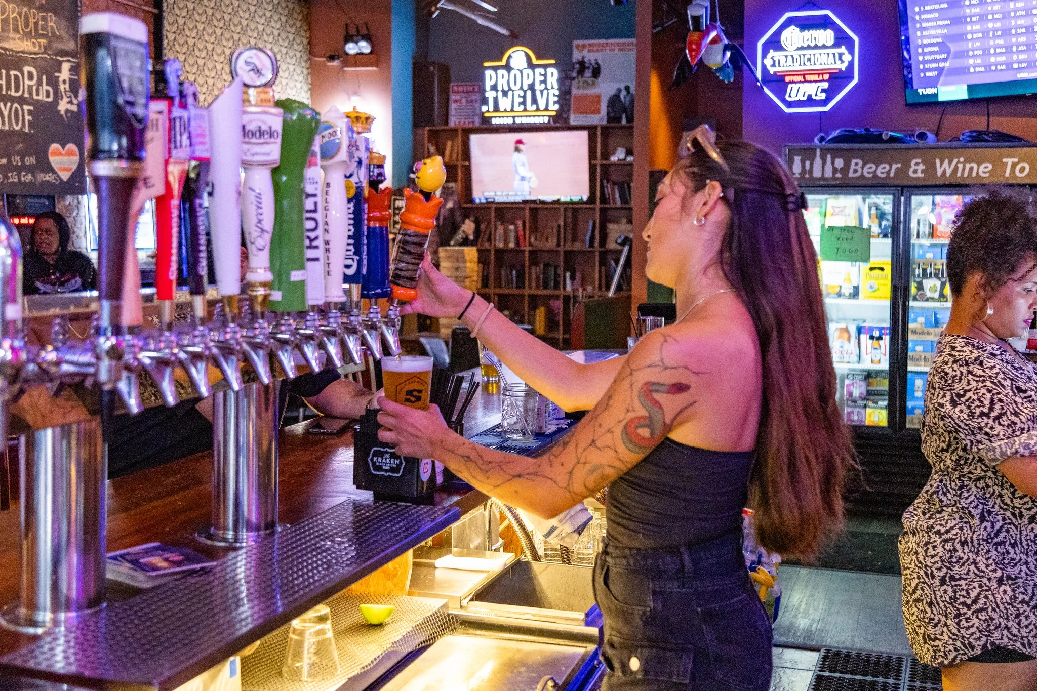 Bartender pouring a draft beer at a lively bar