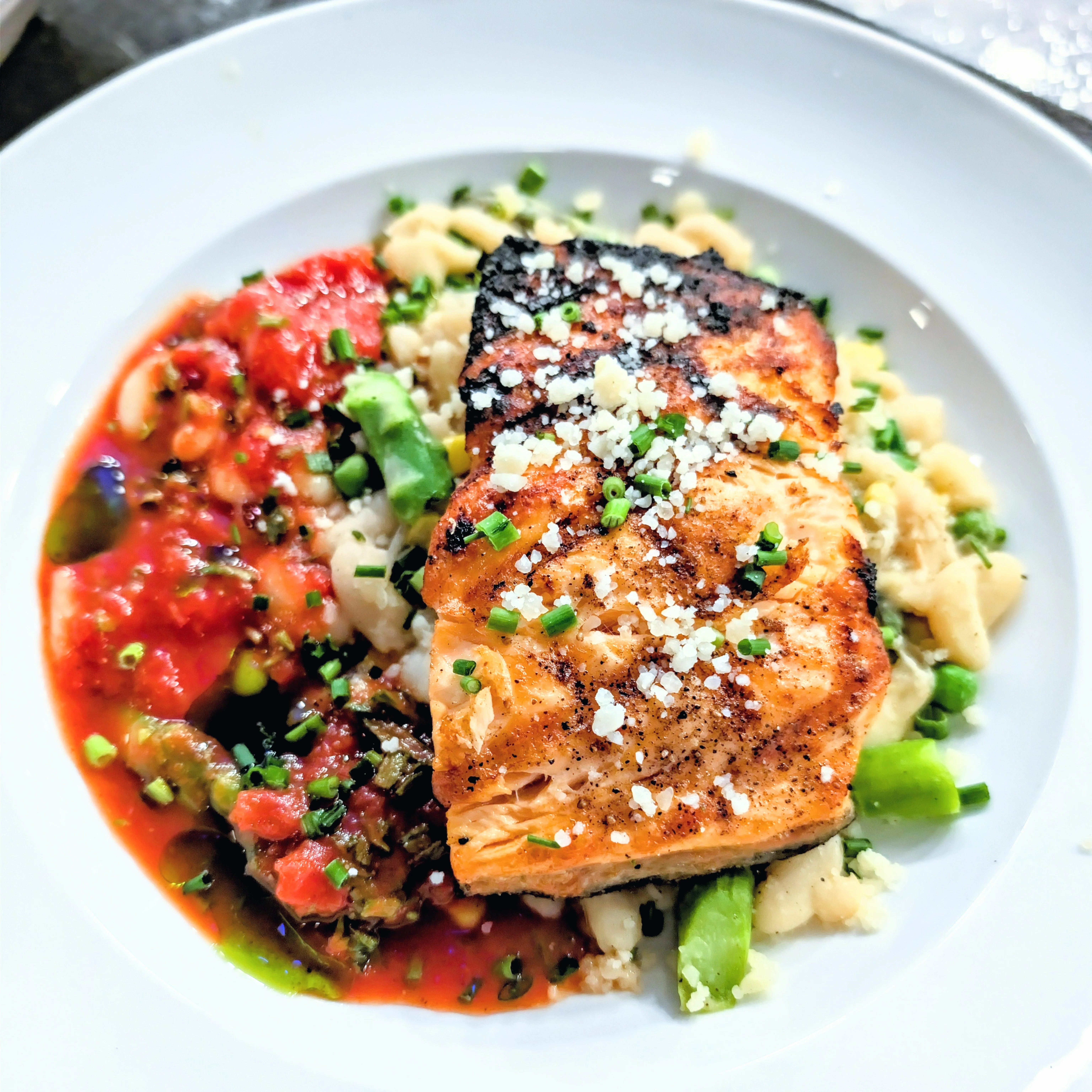A beautifully plated salmon dish served on creamy risotto, garnished with herbs and lemon slices.
