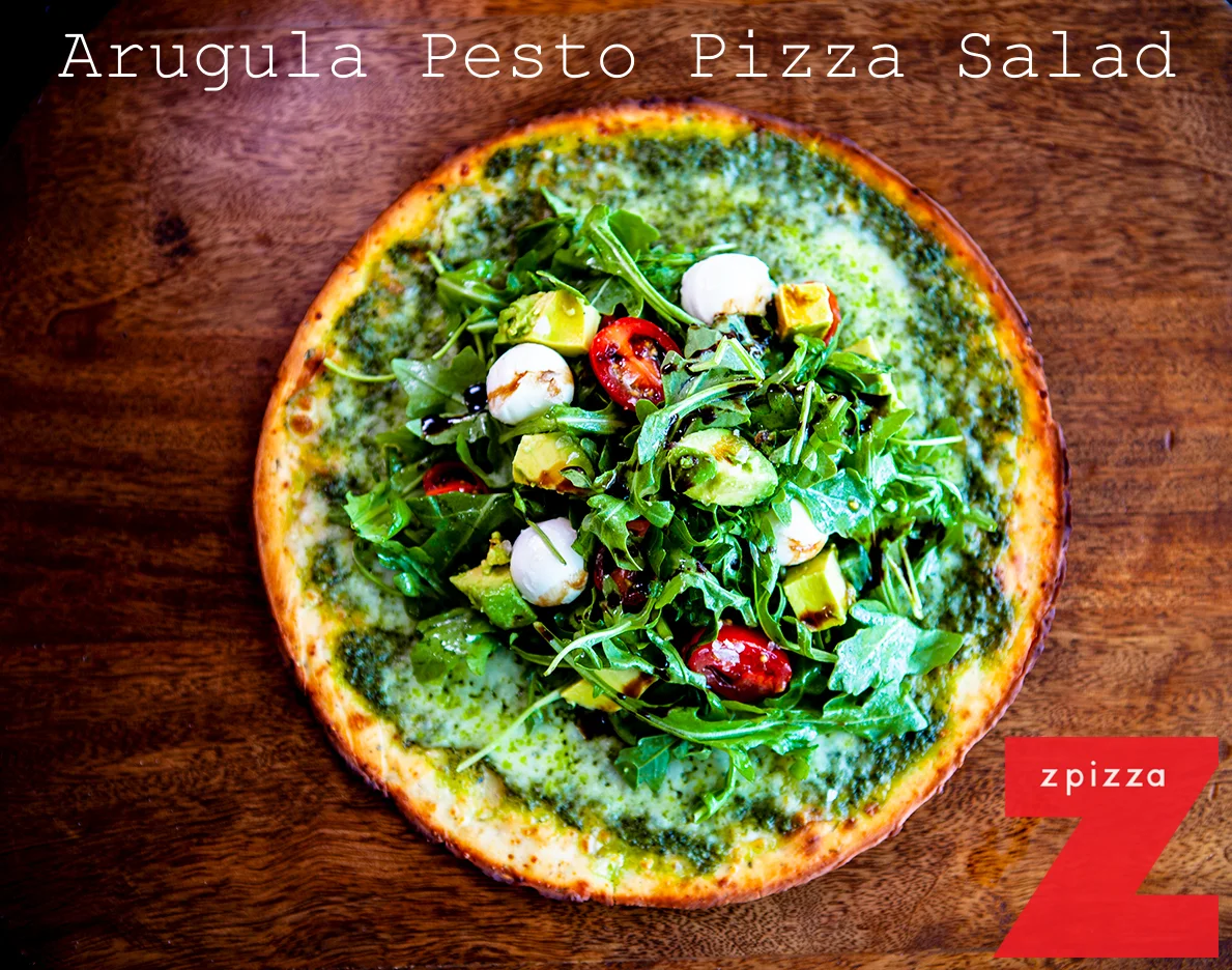 Arugula pesto pizza salad on a wooden table