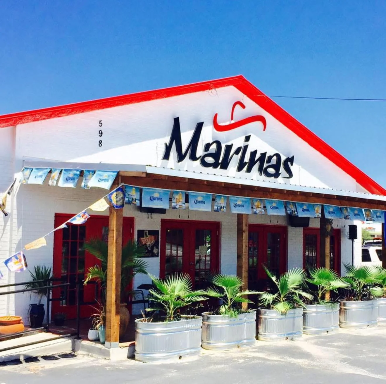 Exterior view of Marinas restaurant with vibrant signage and palm plants
