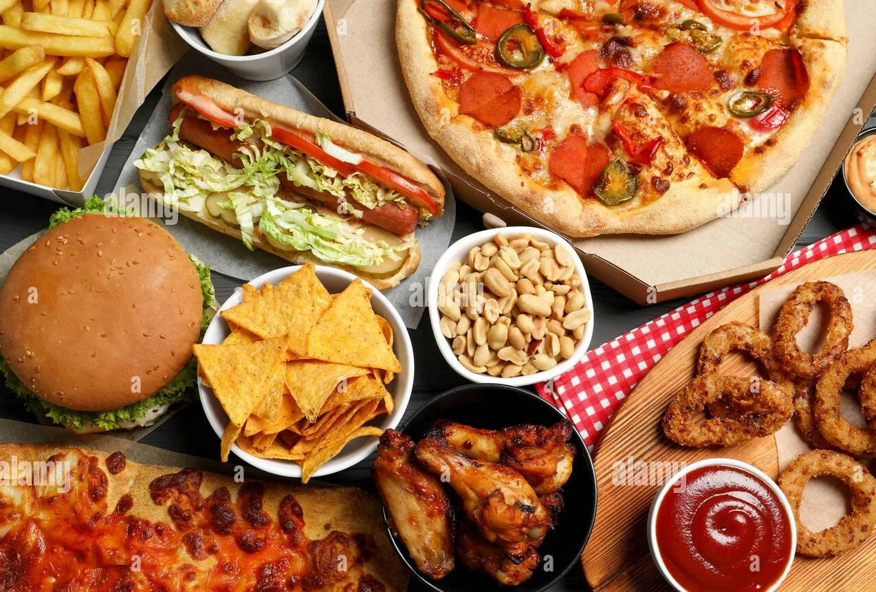 Top view of pizza, chips, and fast food on a table.
