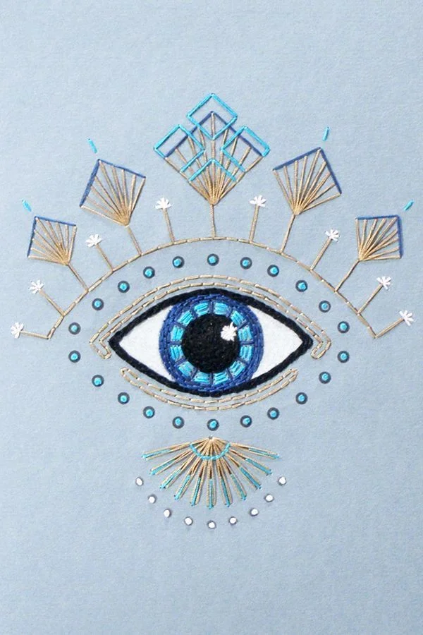 Intricate embroidered eye design on blue fabric