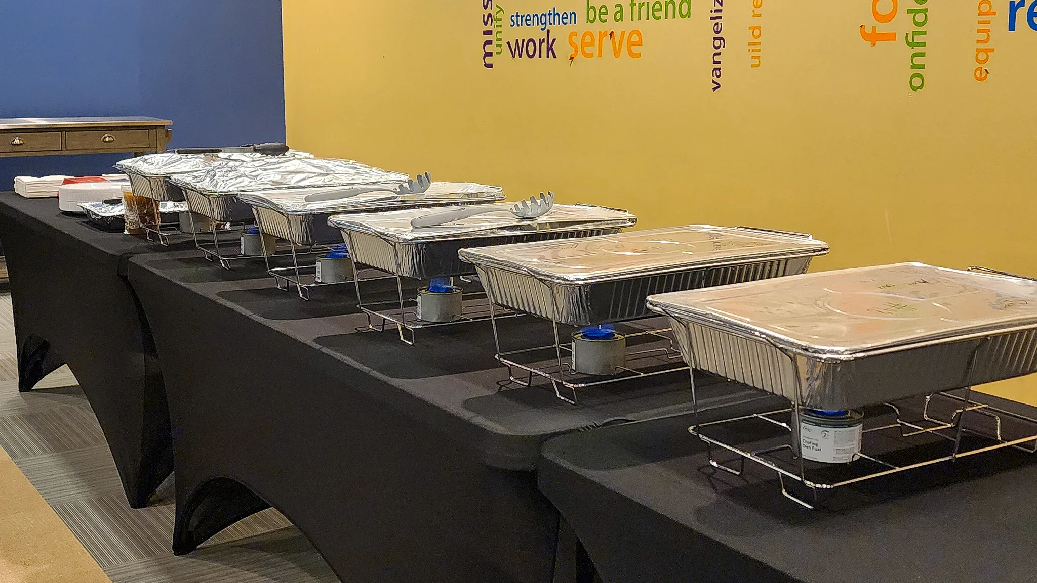 Buffet setup with chafing dishes on a black tablecloth.