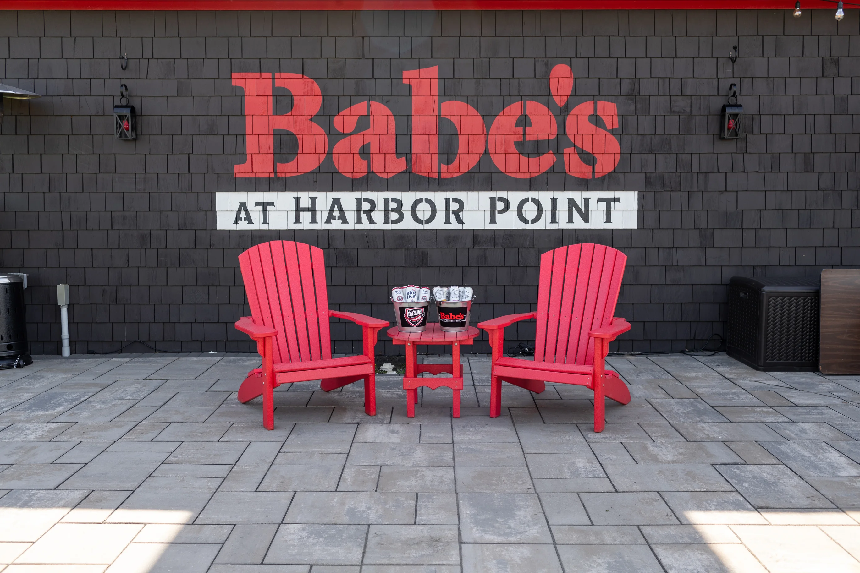 Outdoor seating area with red chairs and restaurant branding on the wall