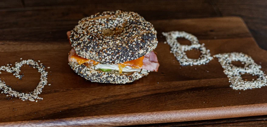 Bagel sandwich with ham and cheese on a wooden board