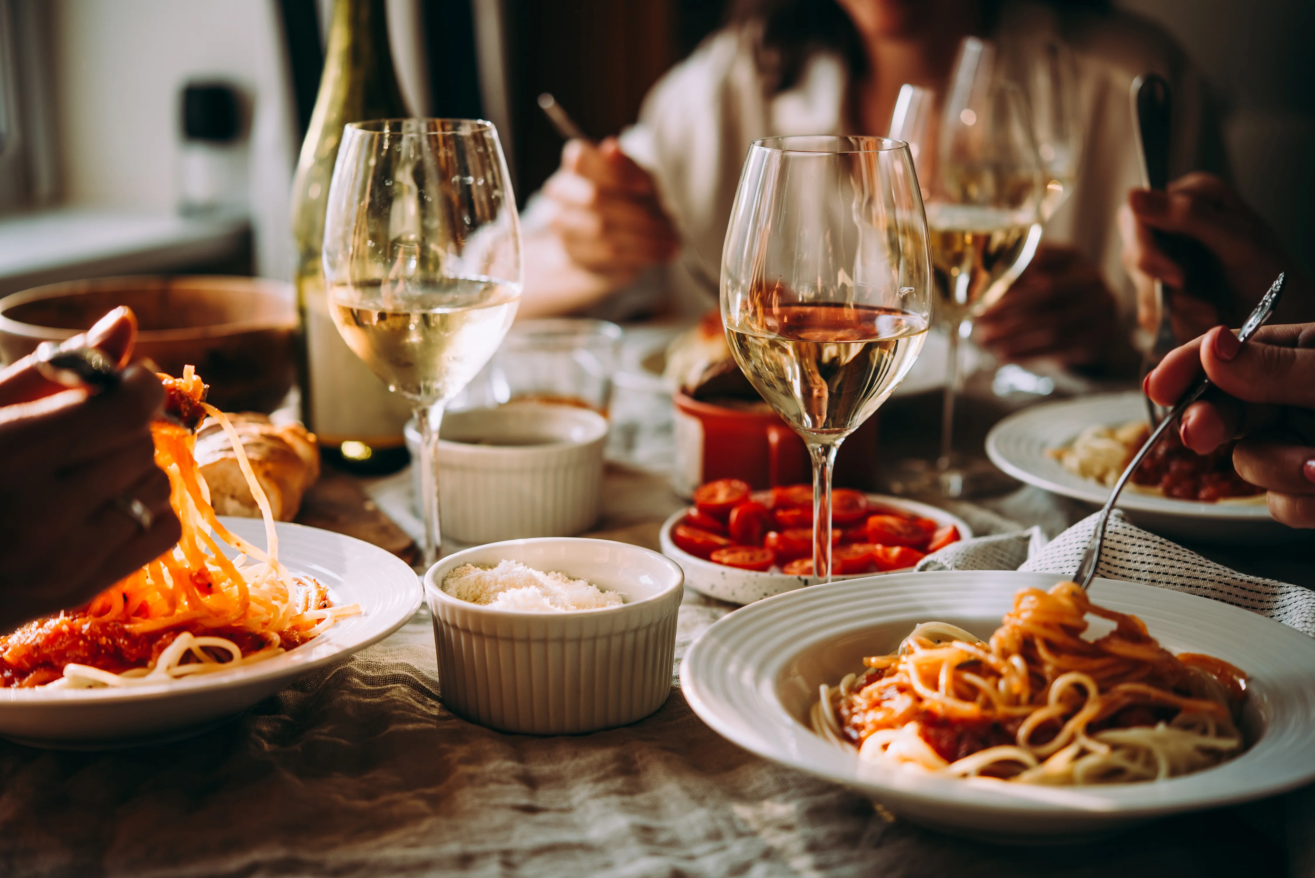 Plate of spaghetti with marinara sauce and wine glasses on a dining table