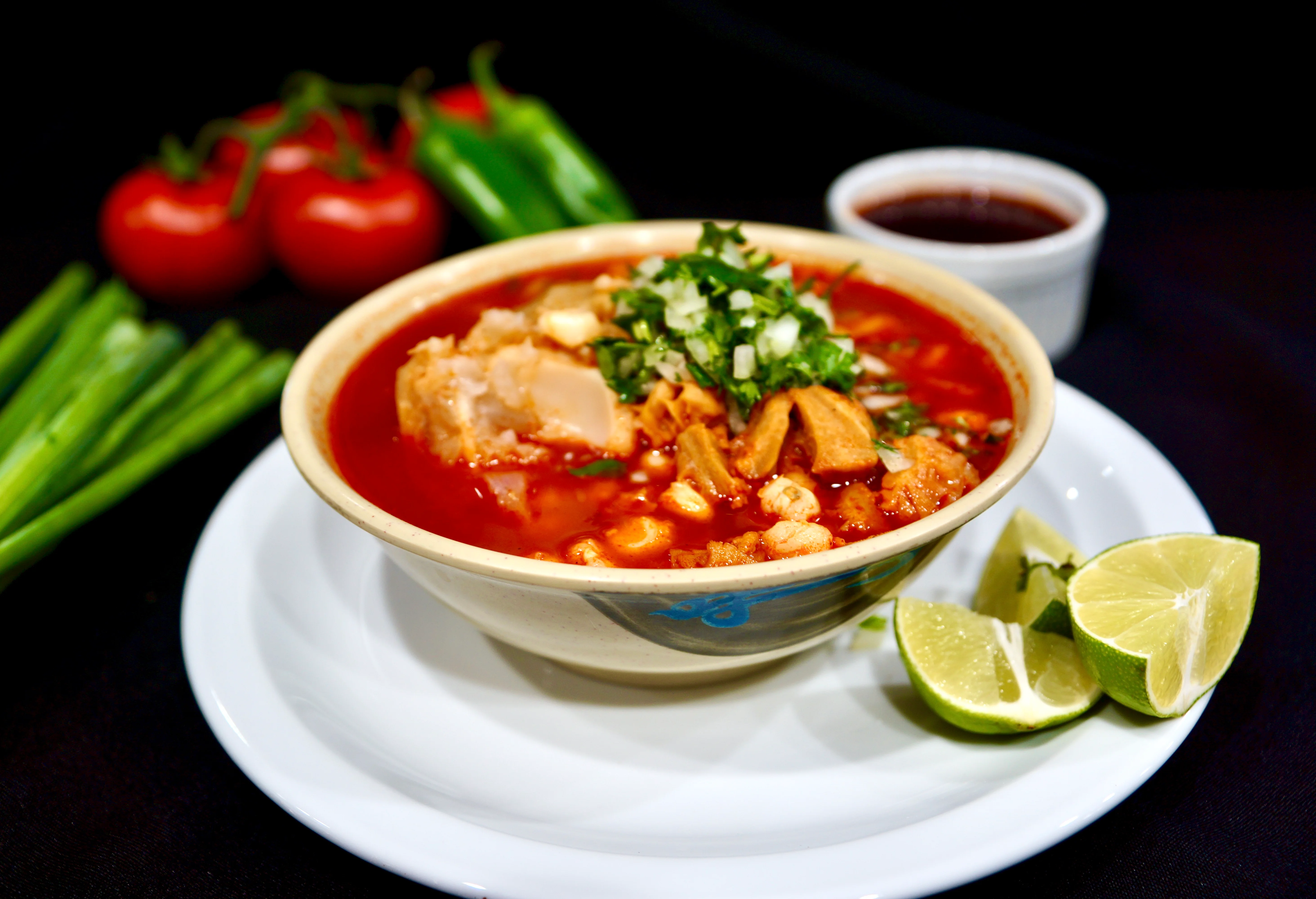 Bowl of Mexican pozole with garnishes and lime