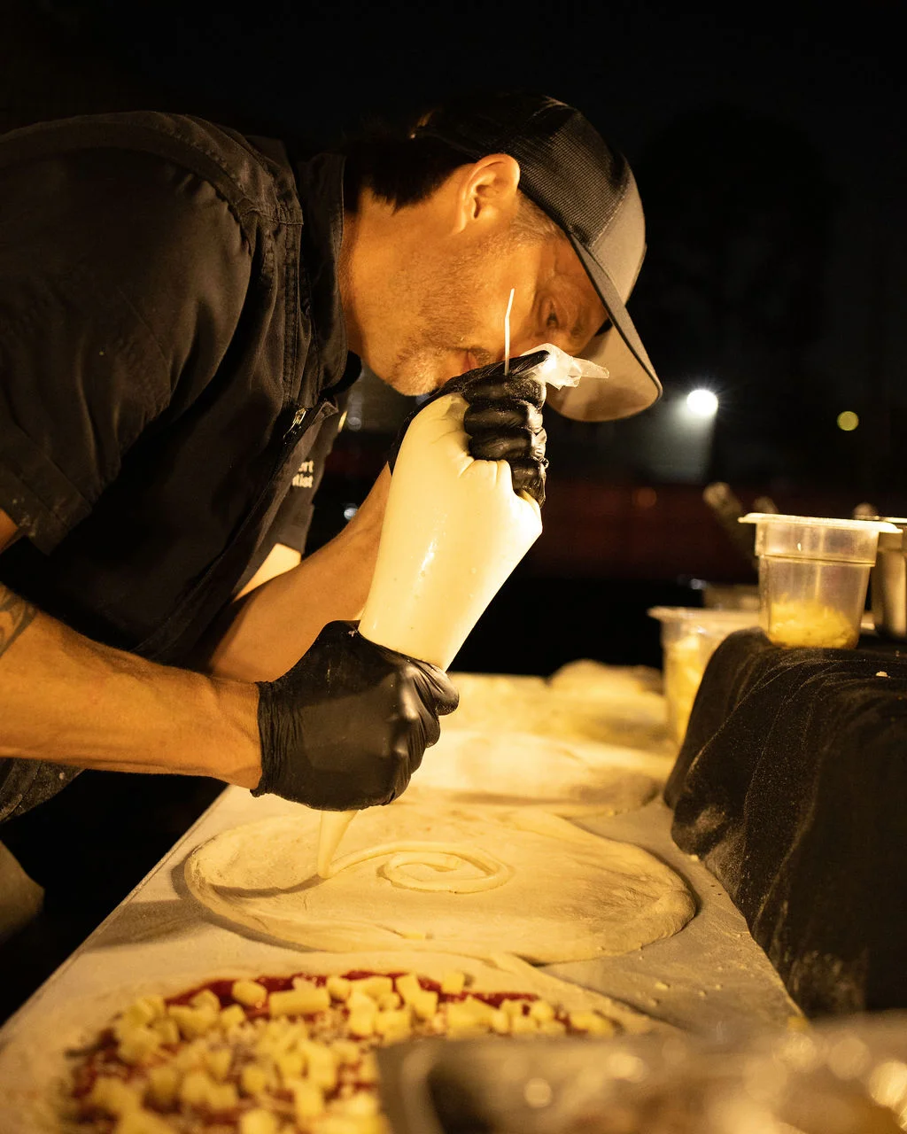 Chef preparing pizza dough with precision at night