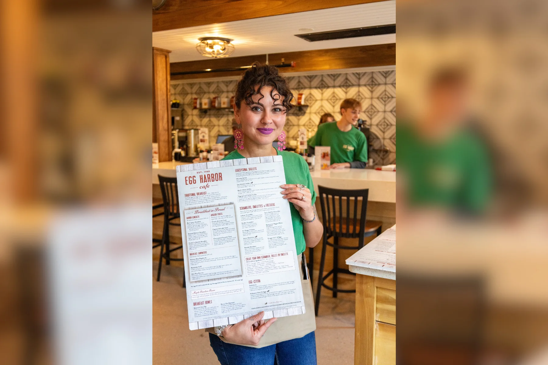 Staff member showcasing the Egg Harbor Cafe menu in a cozy restaurant setting