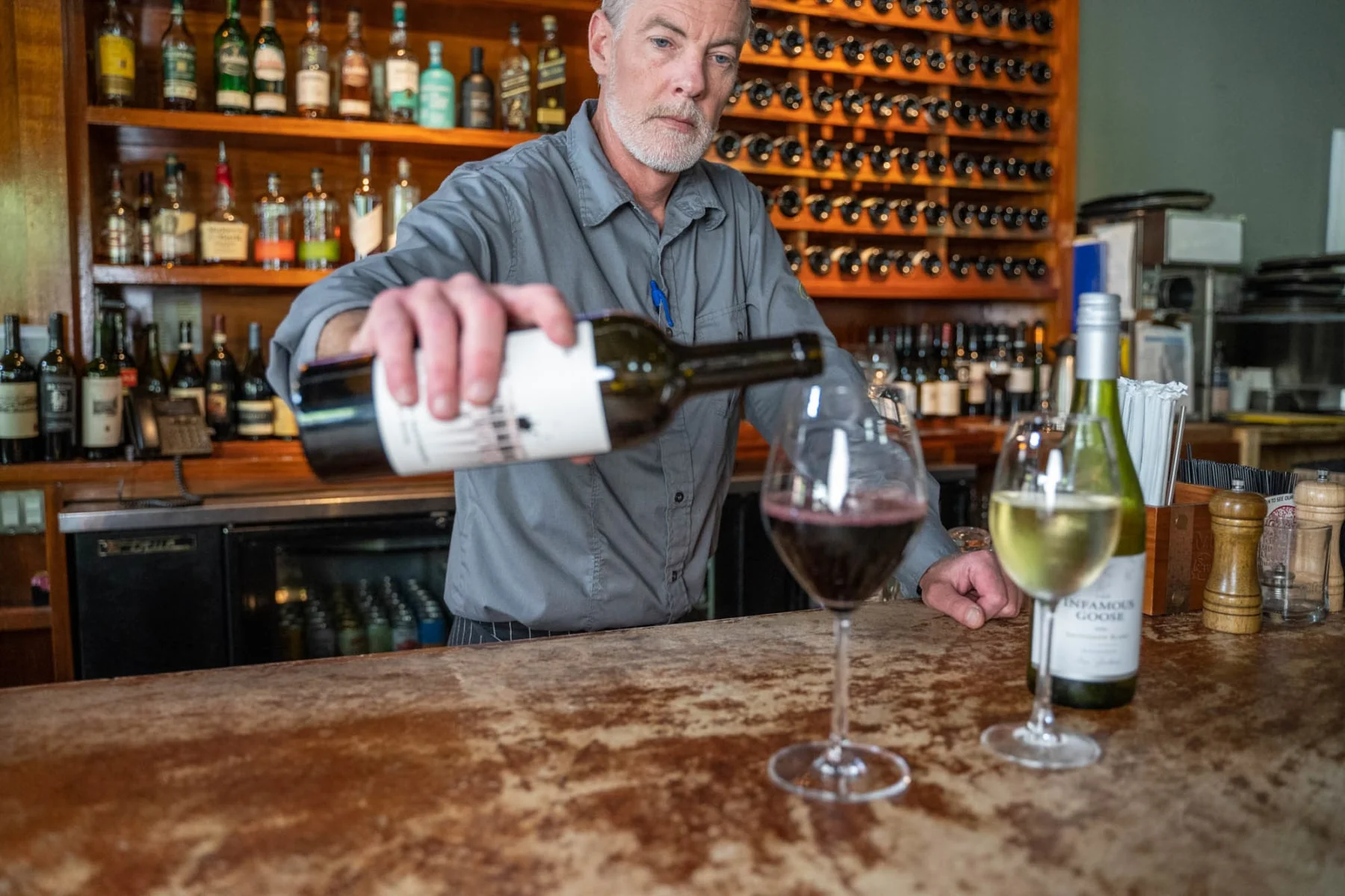 Bartender pouring red wine at a stylish bar