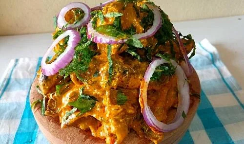 Delicious Indian butter chicken topped with onions and cilantro