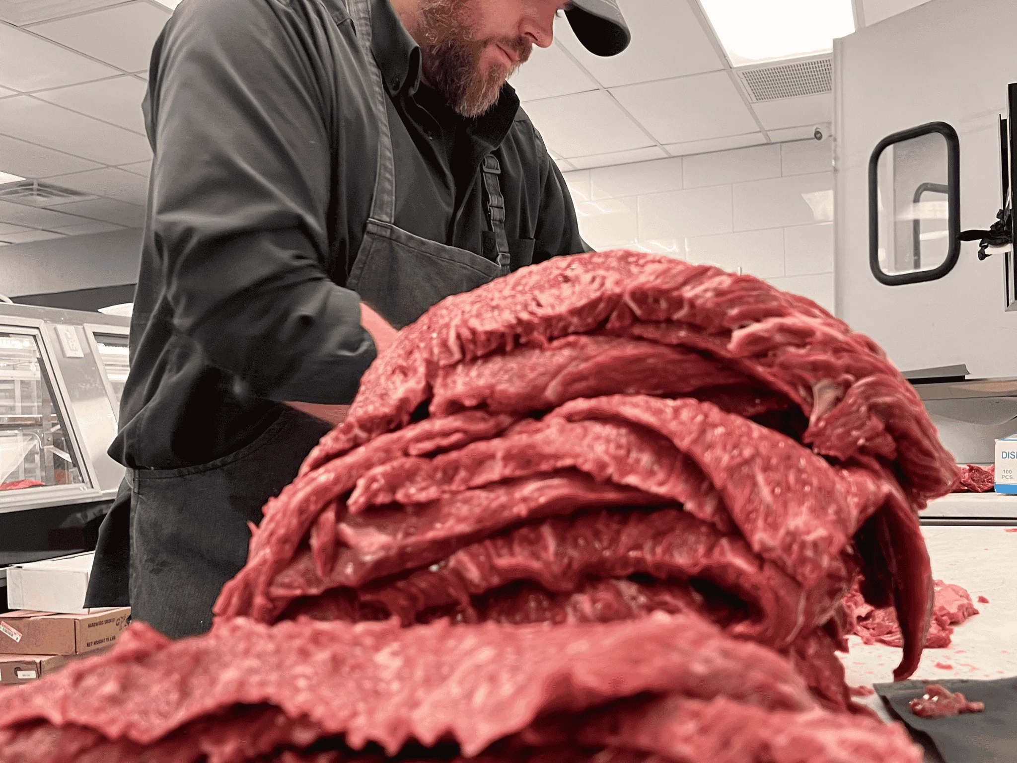 Butcher preparing fresh cuts of meat in a clean kitchen environment.