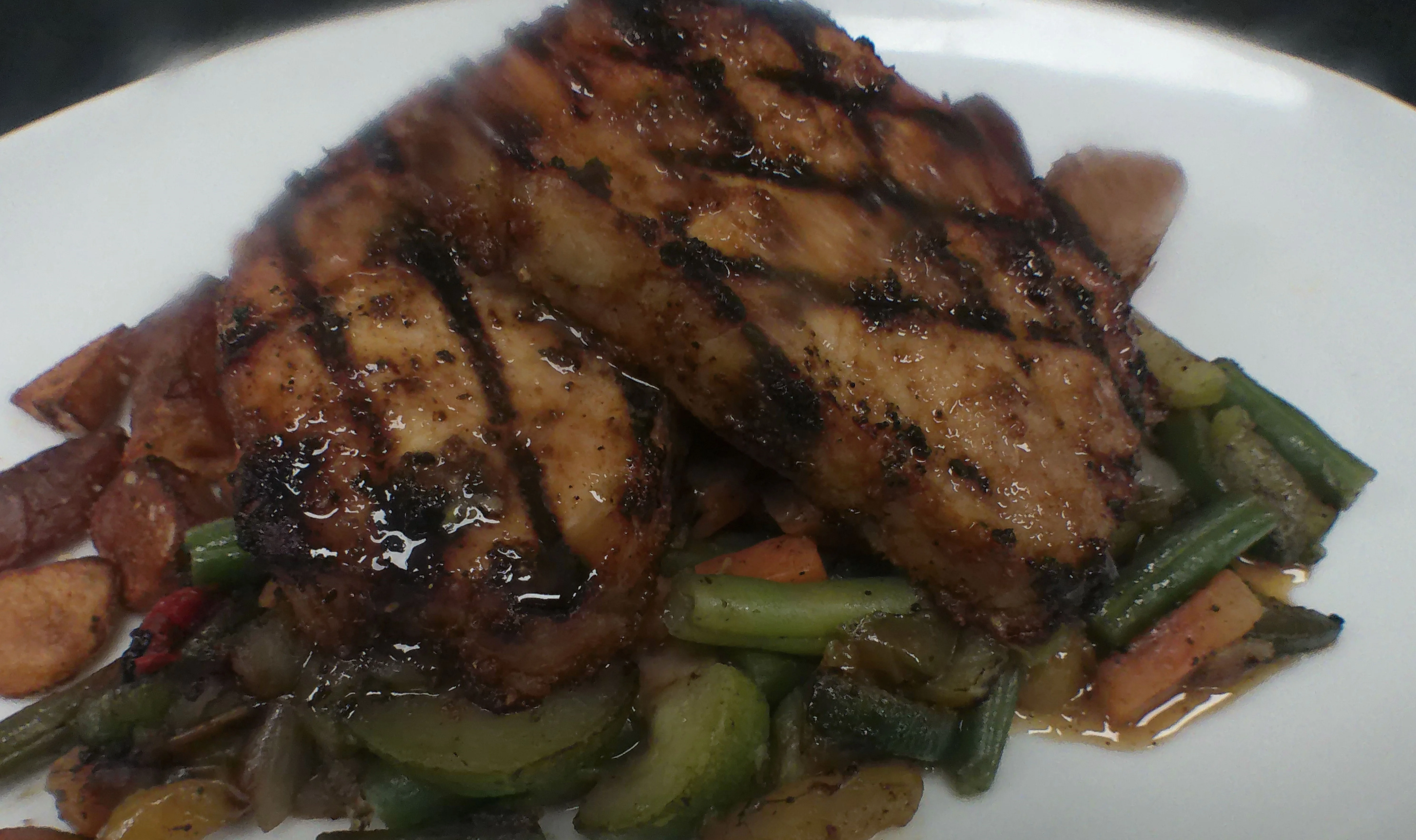 Grilled pork chops served on a bed of sautéed vegetables