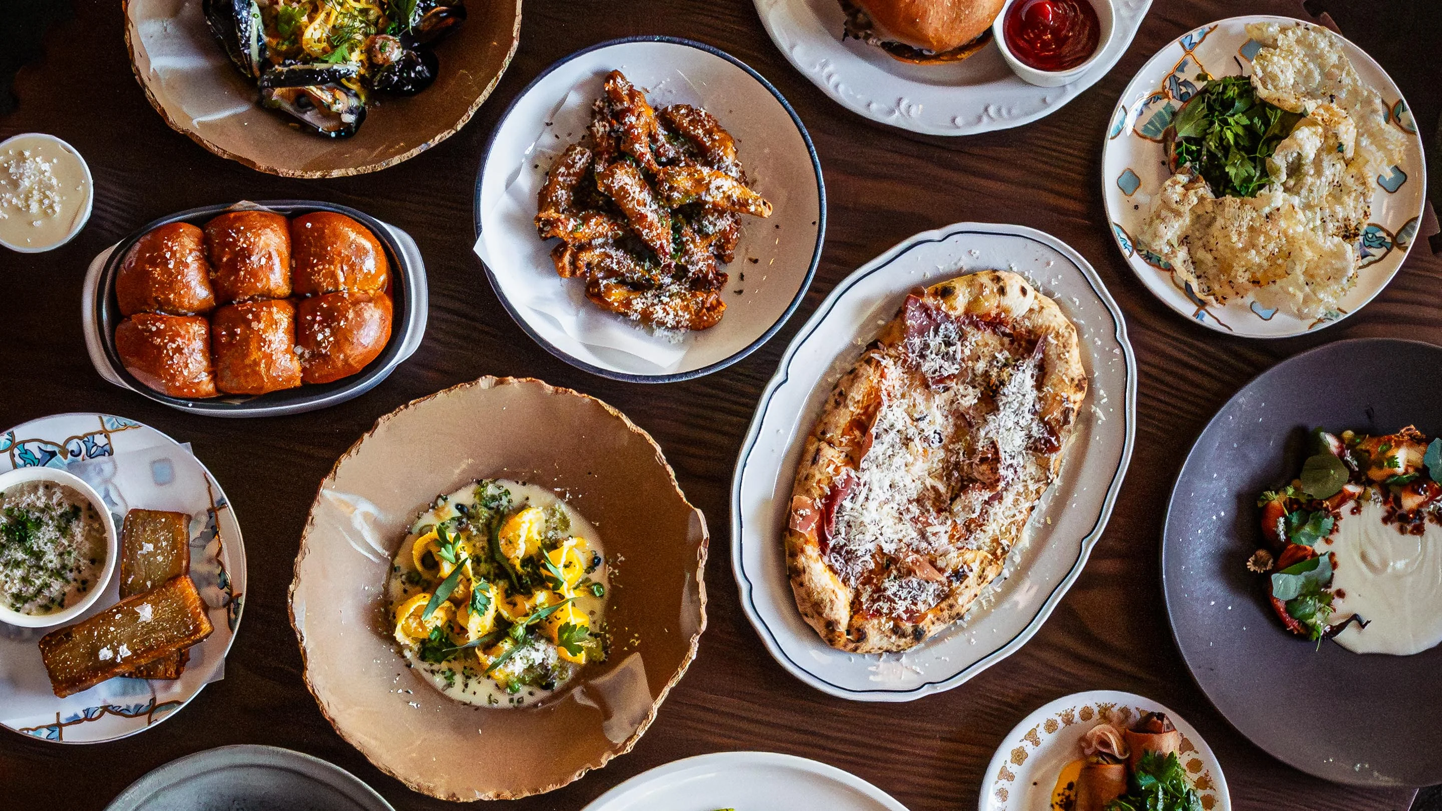 Assorted dishes including pizza and wings in a vibrant restaurant setting