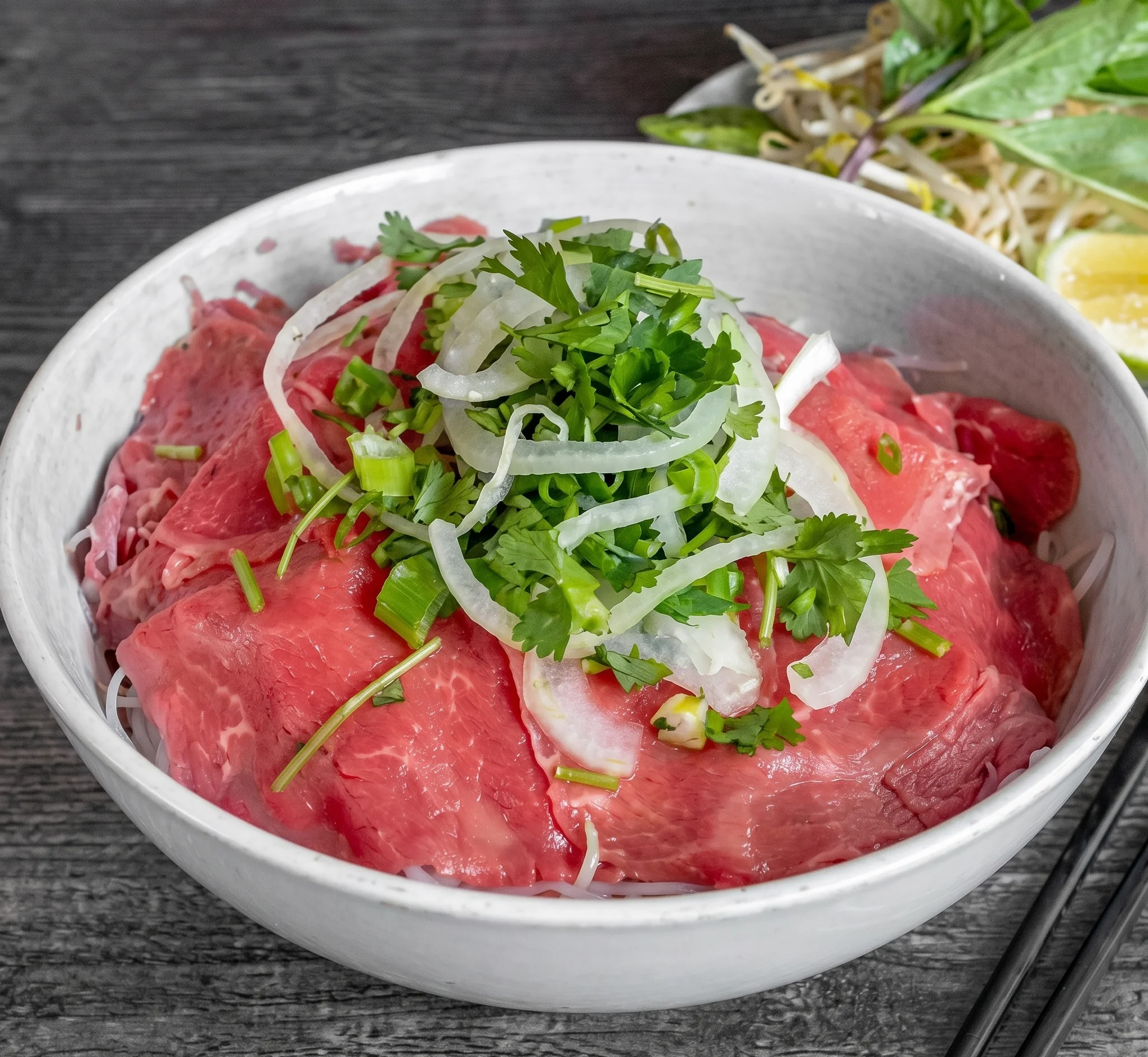 Bowl of Vietnamese pho with rare beef and fresh herbs
