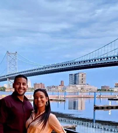 Couple posing by the waterfront with a bridge in the background