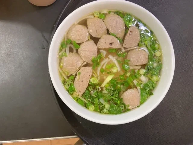 Bowl of Vietnamese pho with meatballs and fresh herbs