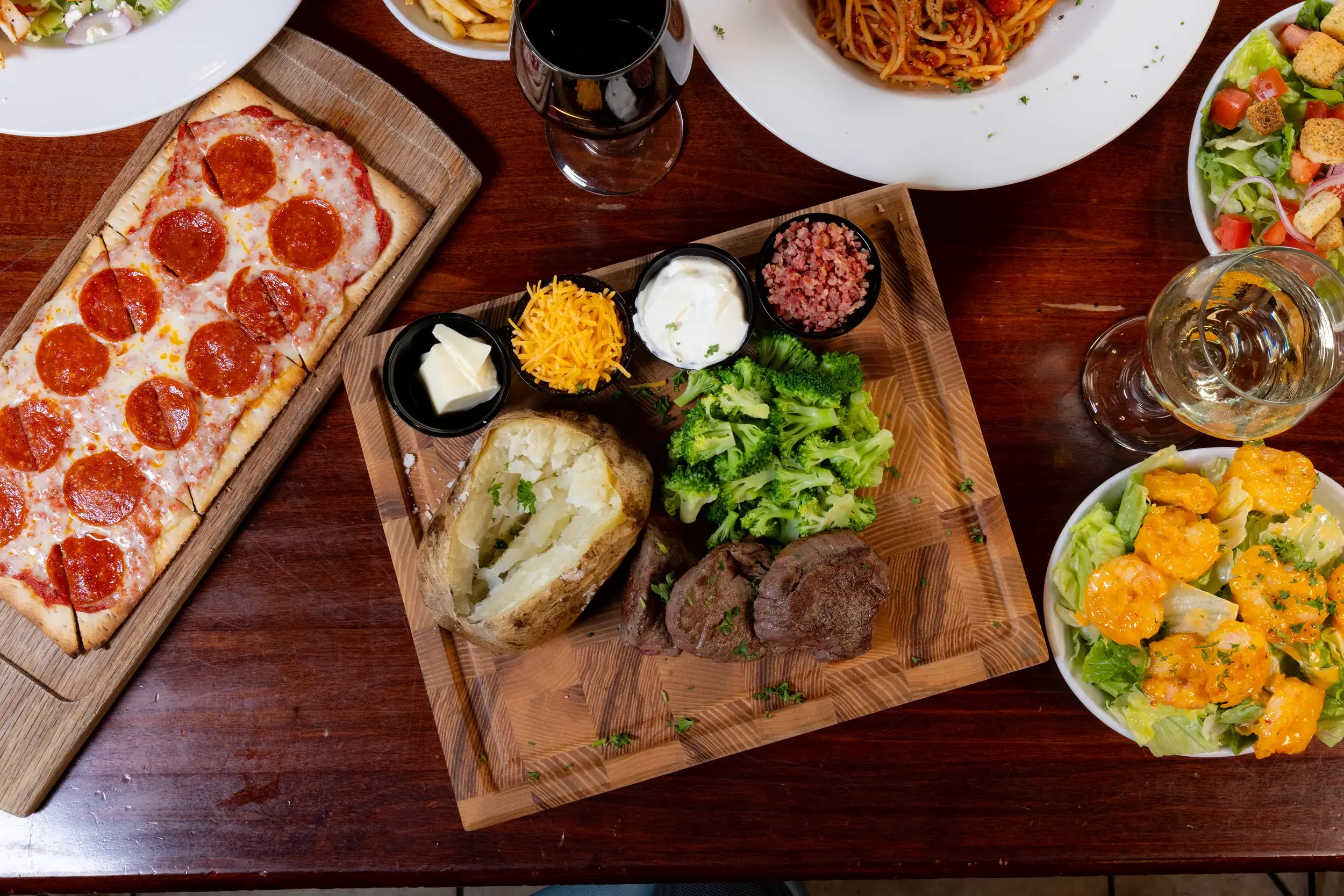 Classic American steak dinner with baked potato and pepperoni pizza