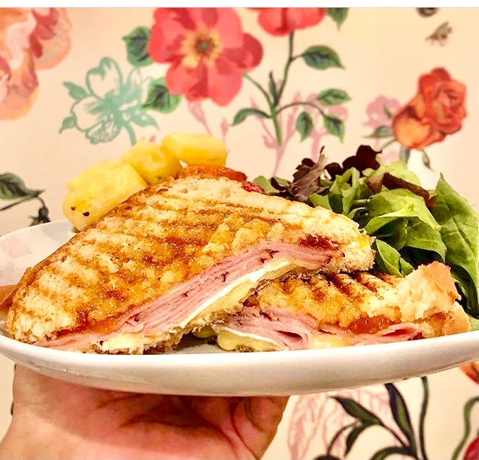Cuban sandwich with ham and cheese served with salad and pineapple