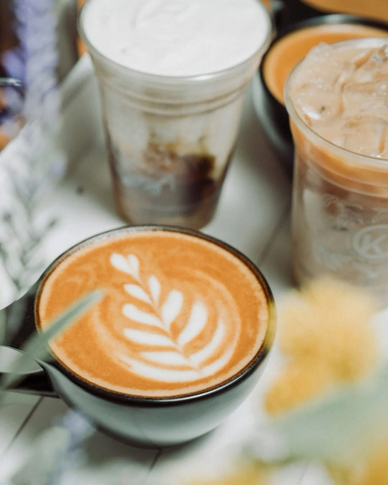 Artisan latte with intricate leaf design in a cozy café setting