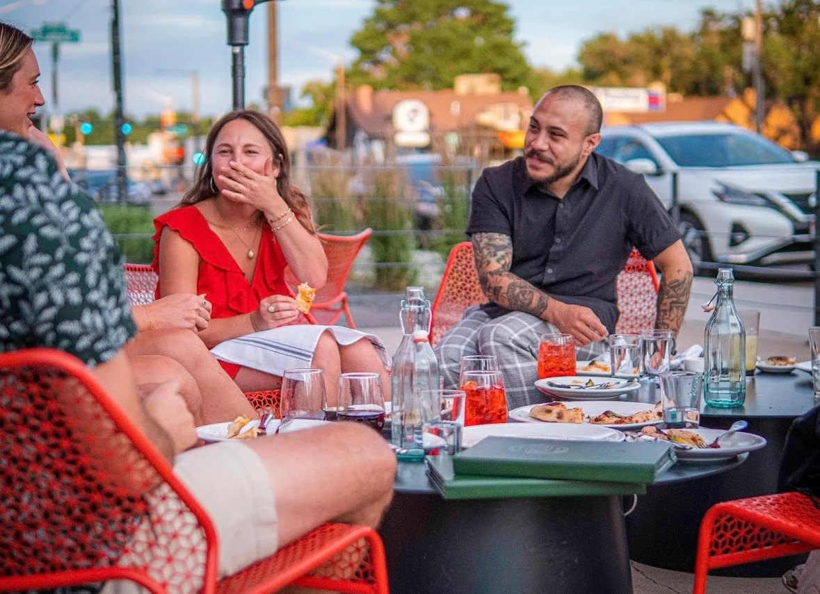 Group of friends enjoying drinks and laughter at an outdoor restaurant