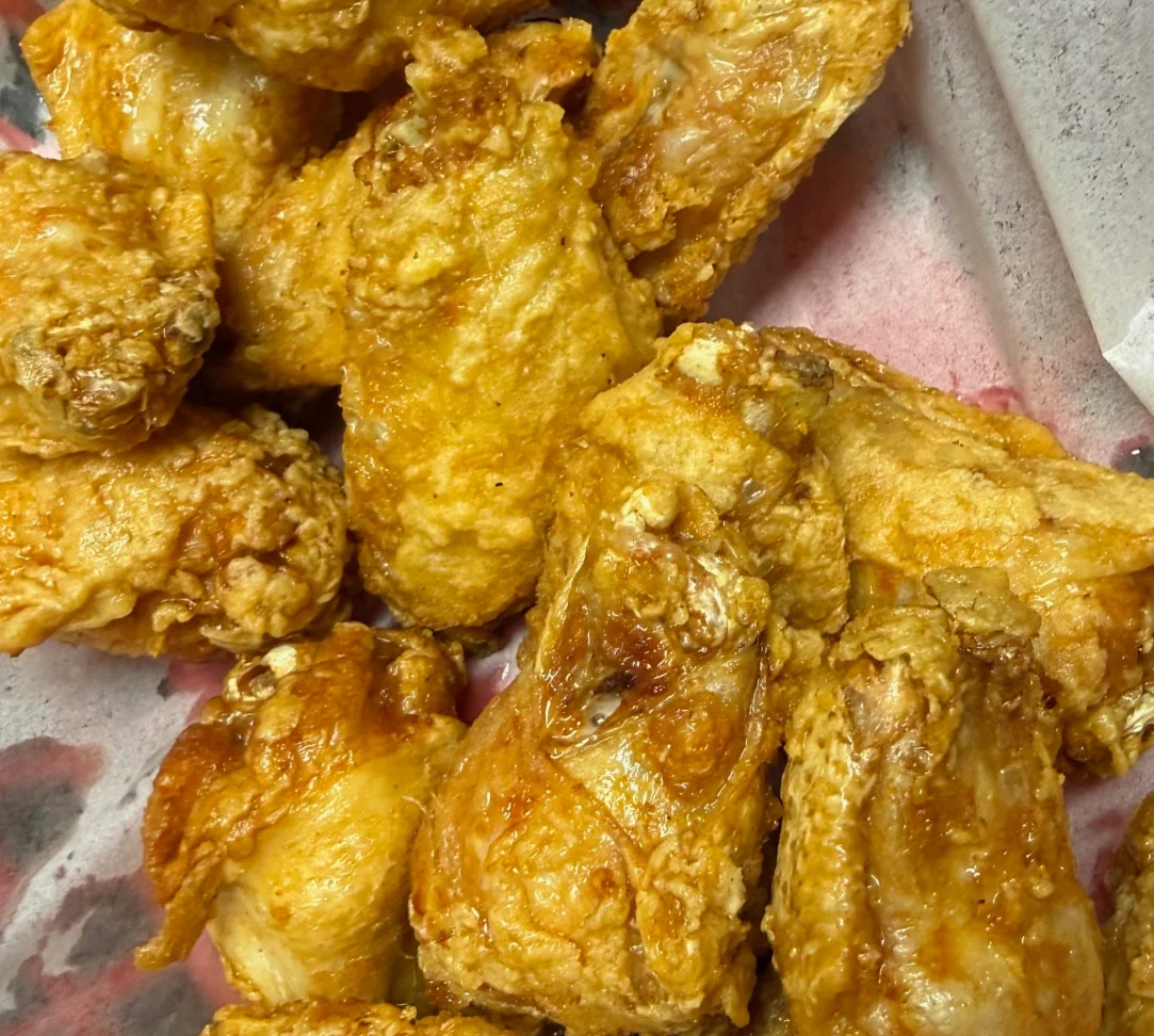 A close-up of crispy fried chicken wings on a serving tray.