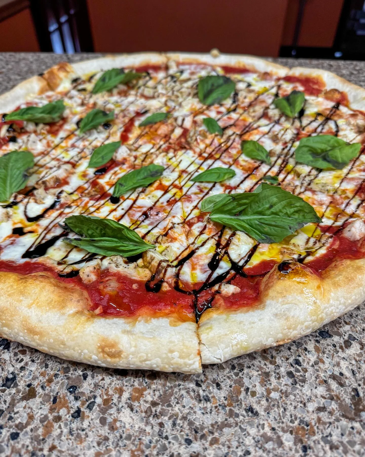Margherita pizza topped with fresh basil and balsamic drizzle