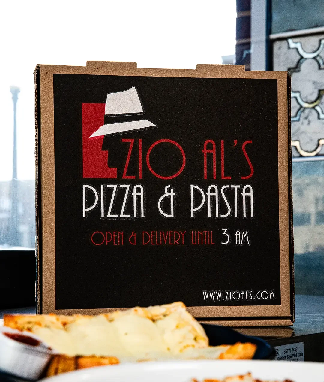 Zio Al's Pizza & Pasta delivery box with food items on a table.