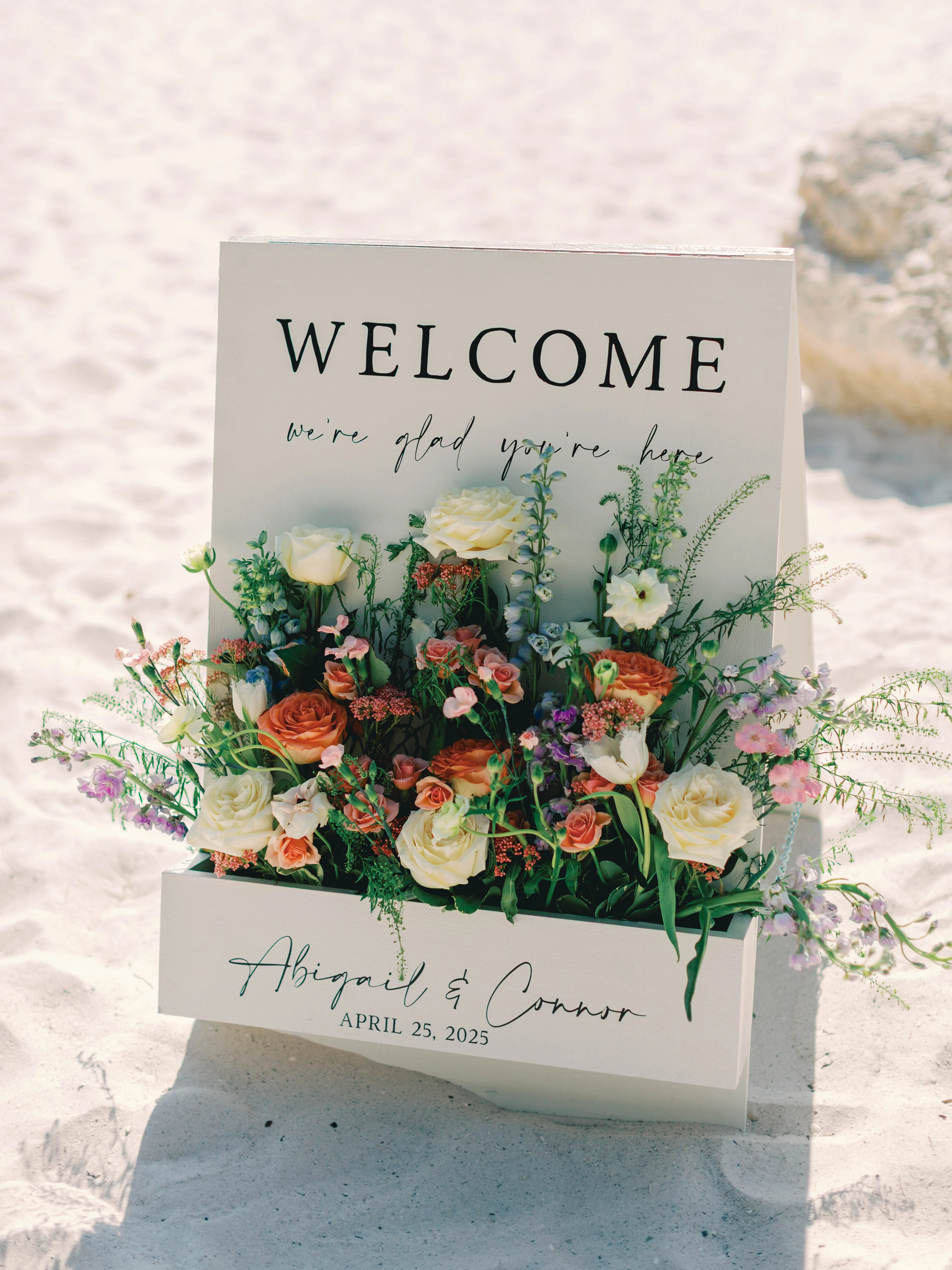 Welcome sign with floral arrangement for a beach wedding