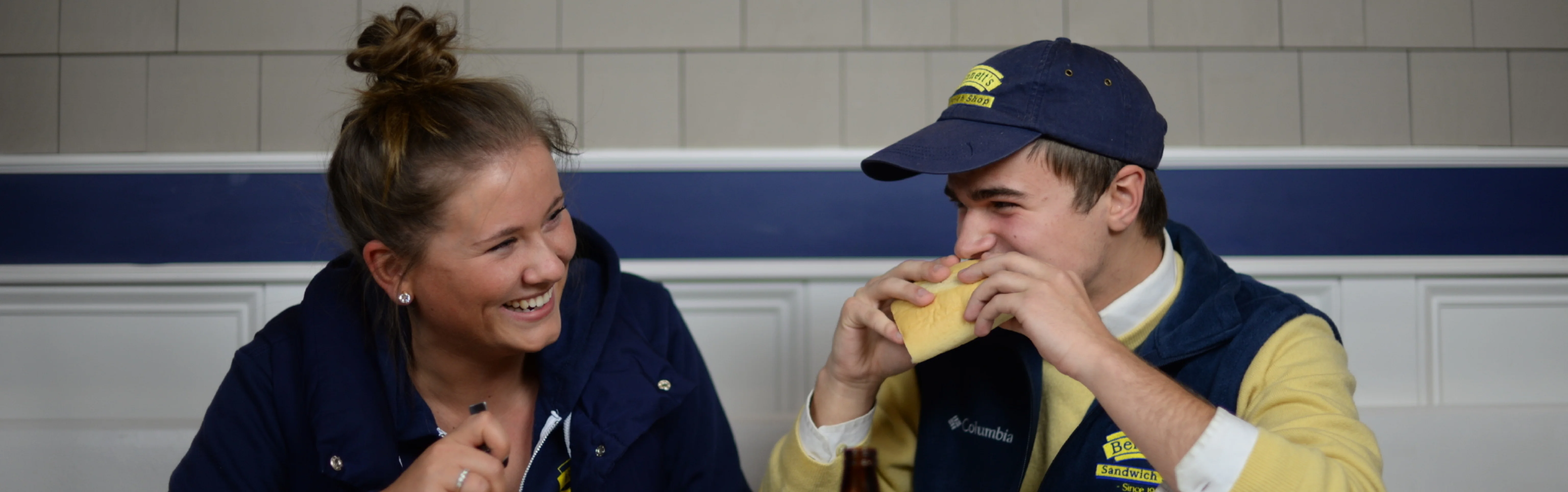 Two friends enjoying sandwiches in a cozy restaurant setting