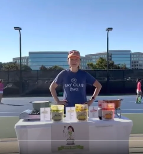 Person at a food stand promoting healthy snacks at a tennis event