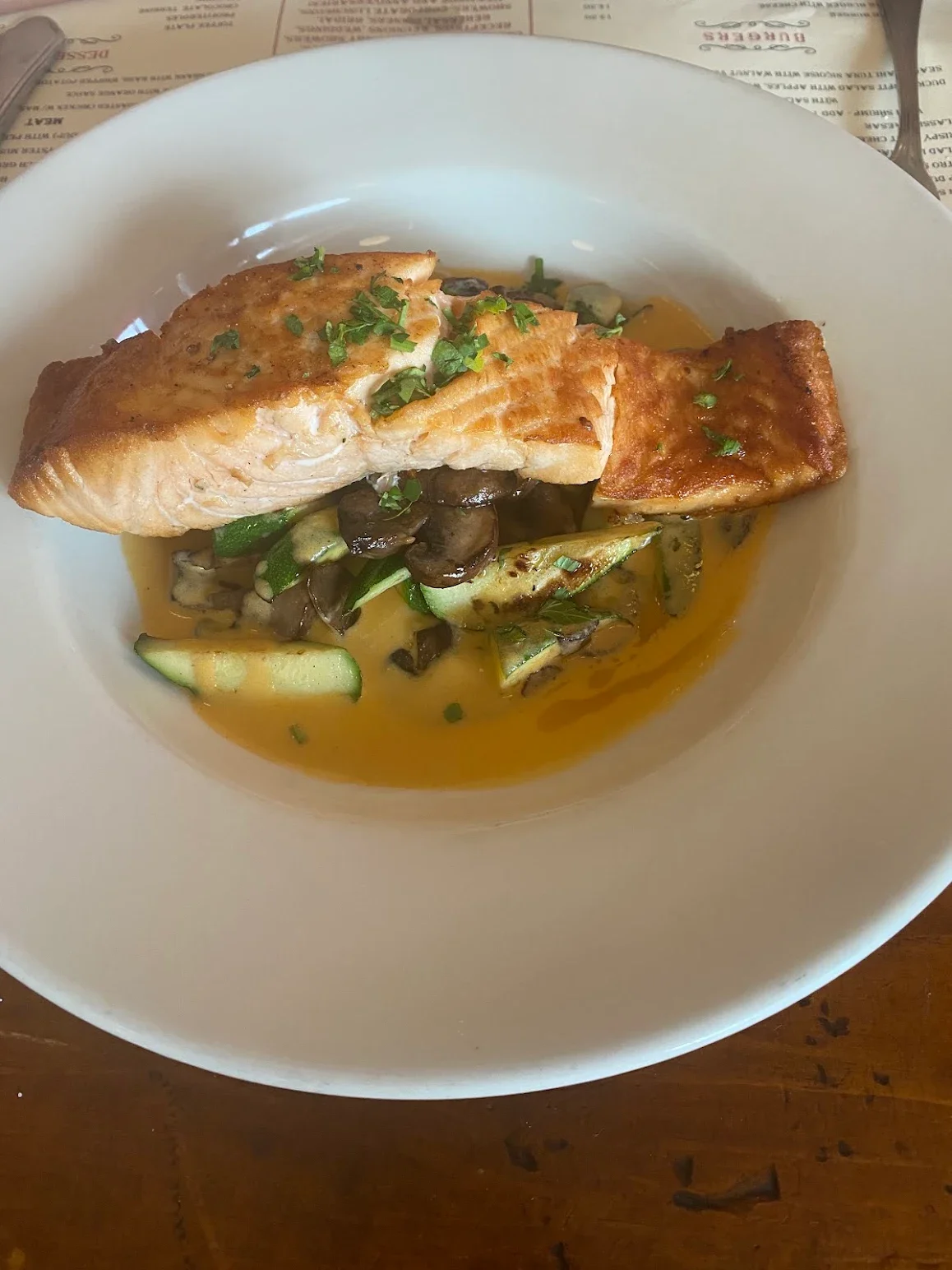 Pan-seared salmon fillet with sautéed vegetables in a rich sauce