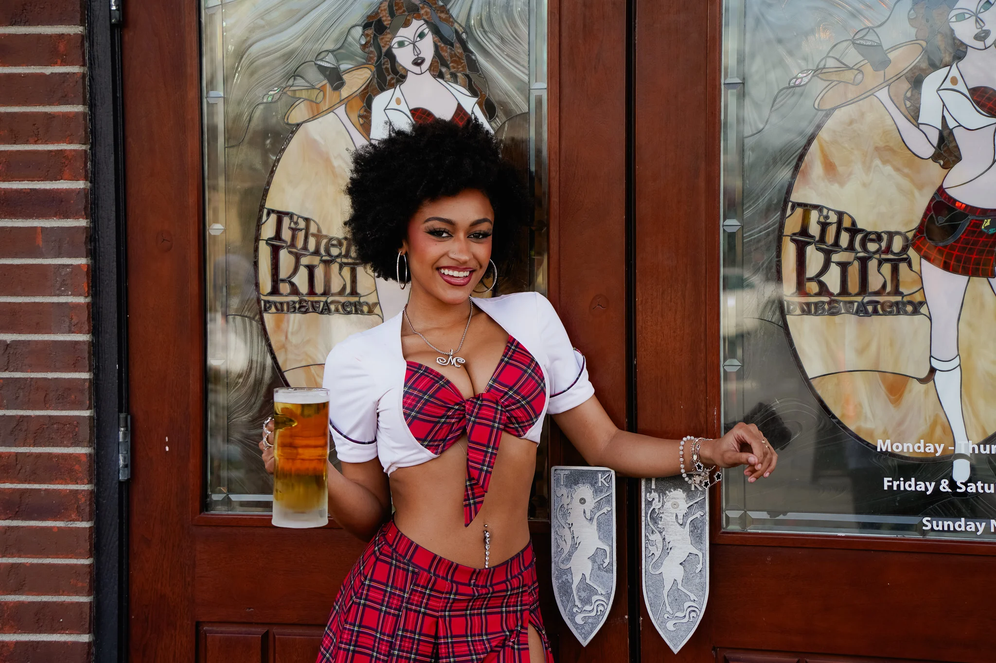 Smiling server holding a beer outside a pub with a vibrant sign