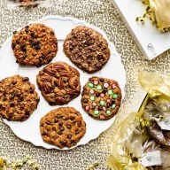 A plate of assorted cookies with chocolate chips, nuts, and colorful candies.