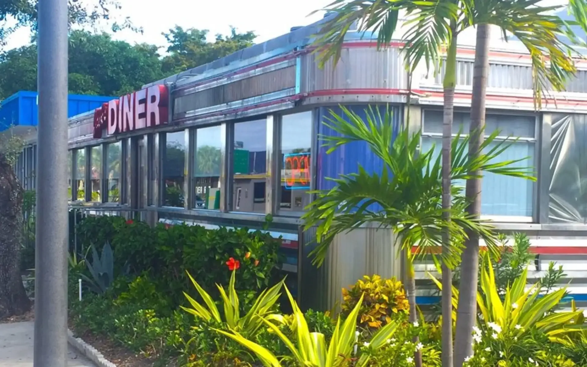 Side view of Moonlite Diner showcasing its iconic retro stainless steel exterior surrounded by lush tropical landscaping in South Florida.