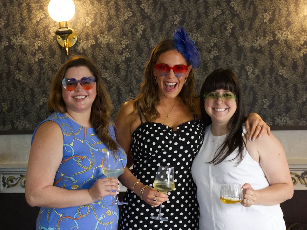 Three friends celebrating with drinks and colorful sunglasses