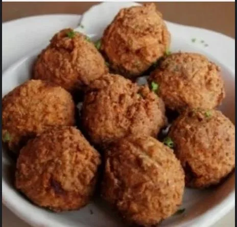 A bowl filled with golden-brown fried balls, likely a popular appetizer, arranged neatly and garnished.