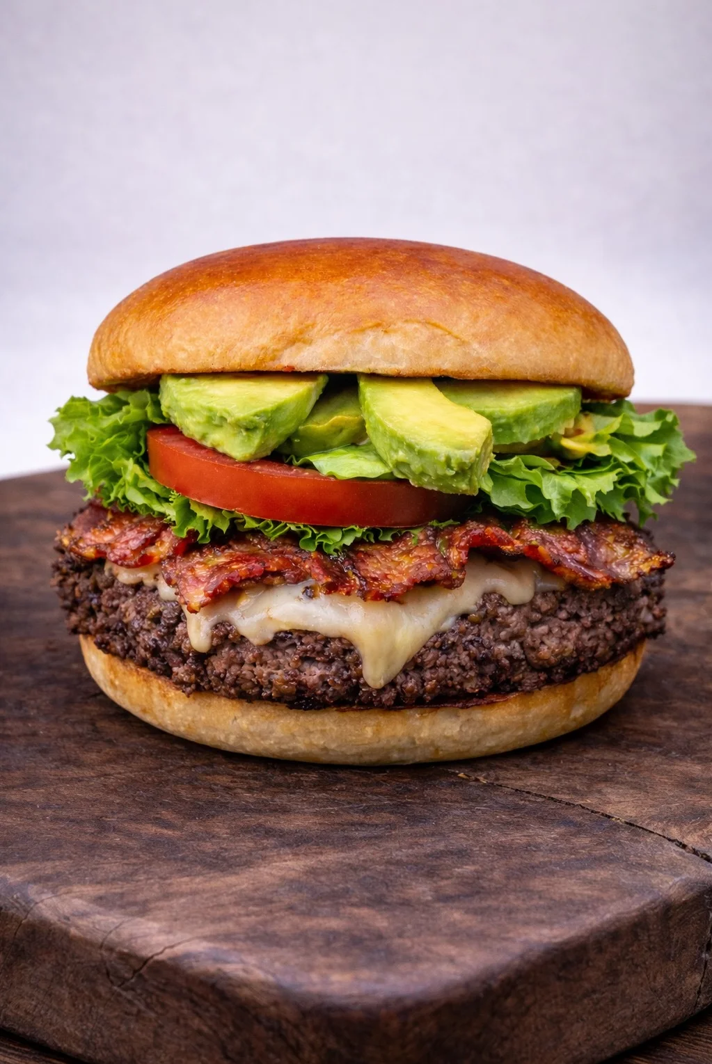 Juicy American bacon cheeseburger with fresh toppings on a wooden board