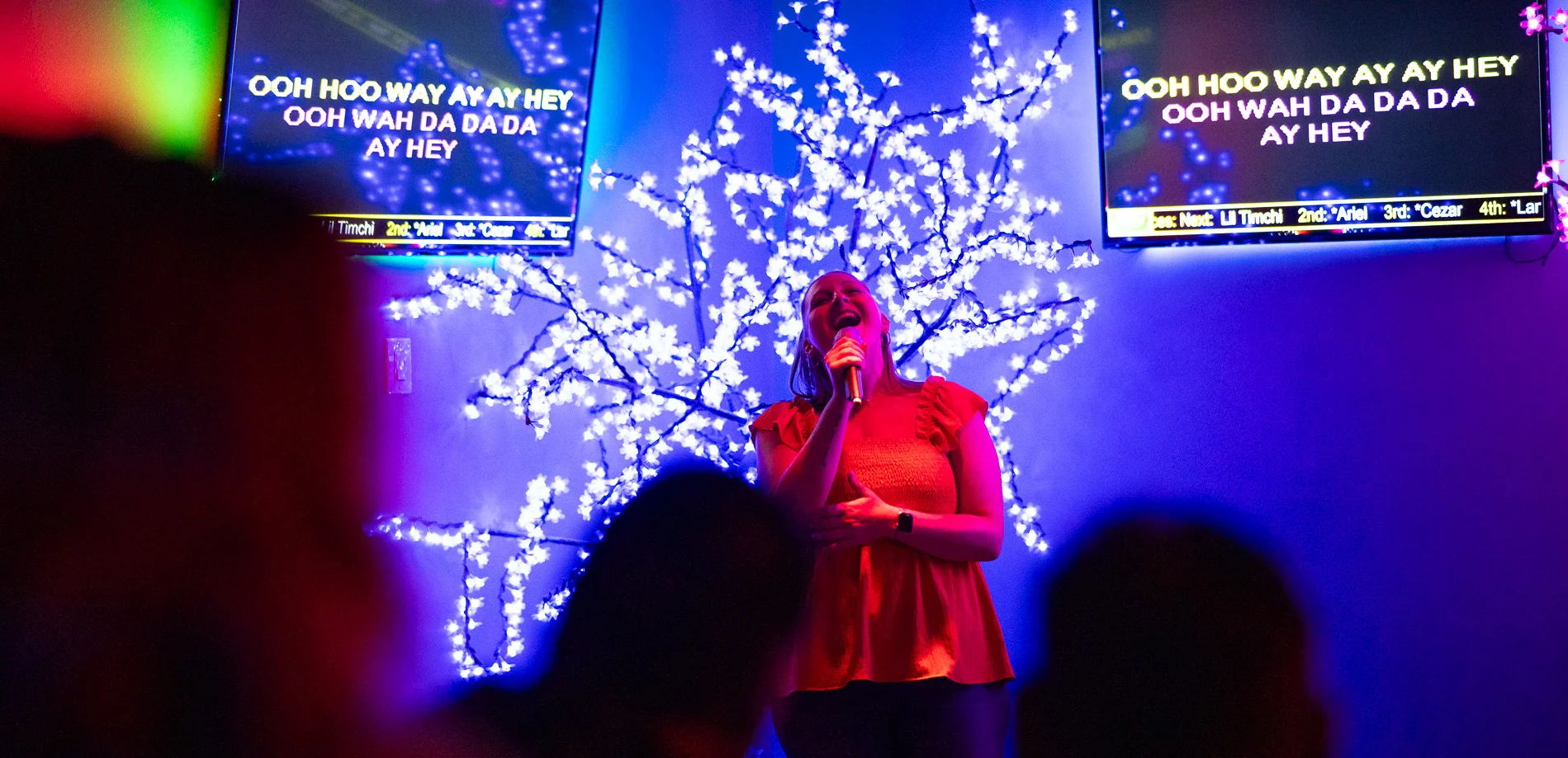 Singer performing karaoke in a vibrant bar setting