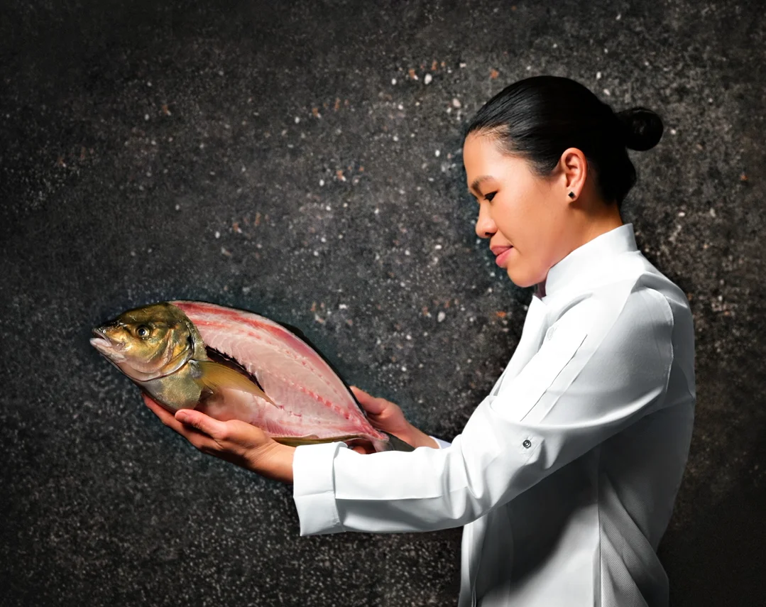 Chef meticulously plating a dish with precision using chopsticks