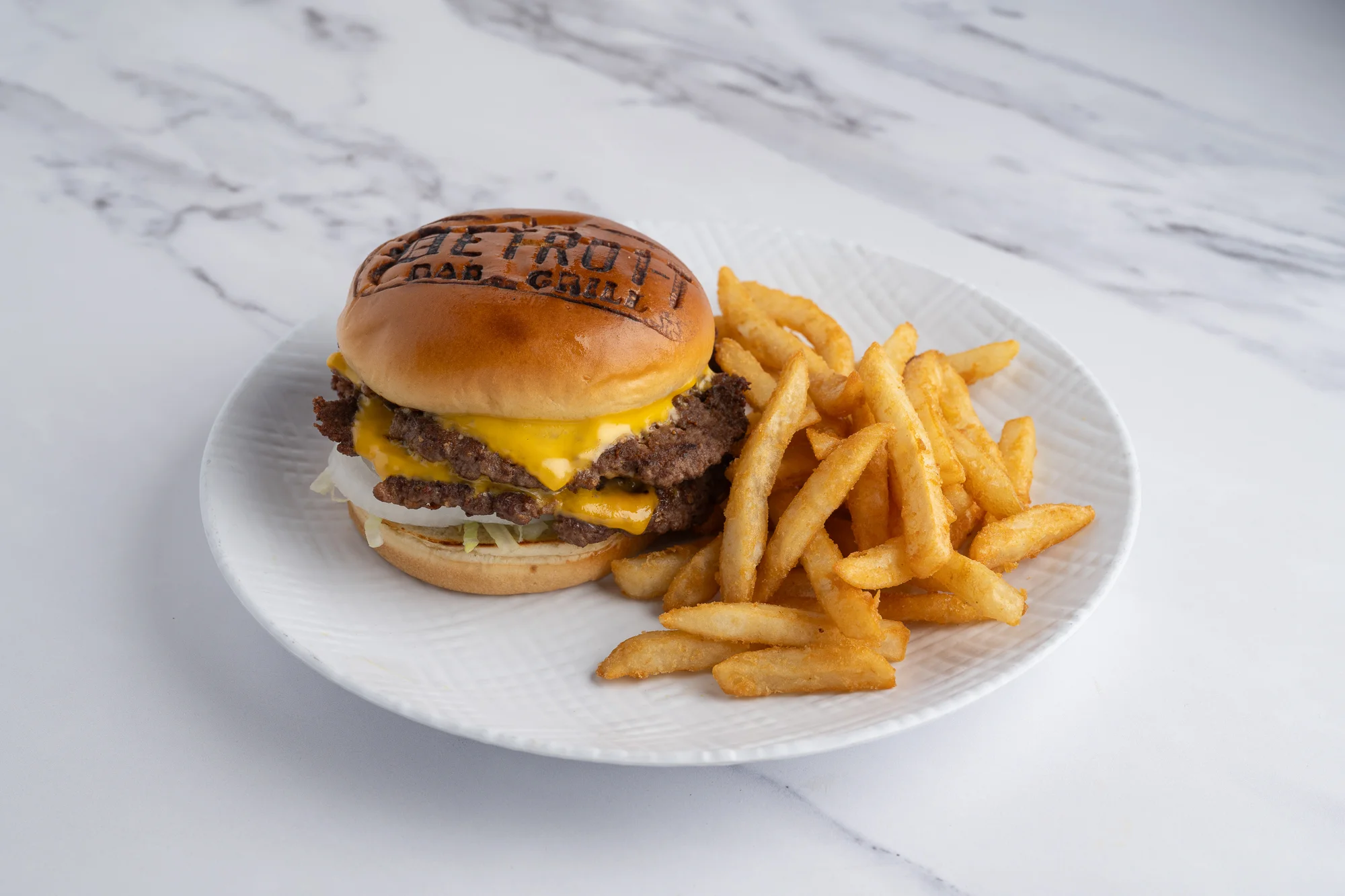 Juicy cheeseburger with fries on a white plate