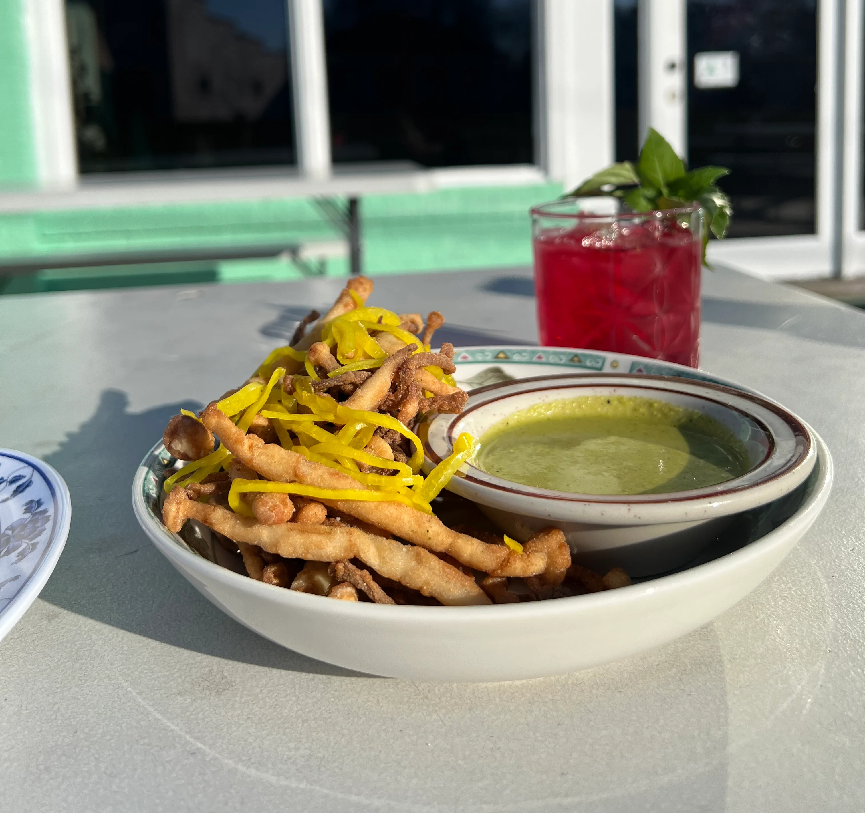 A plate of dumplings drizzled with sauce and garnished with herbs, alongside a food magazine.