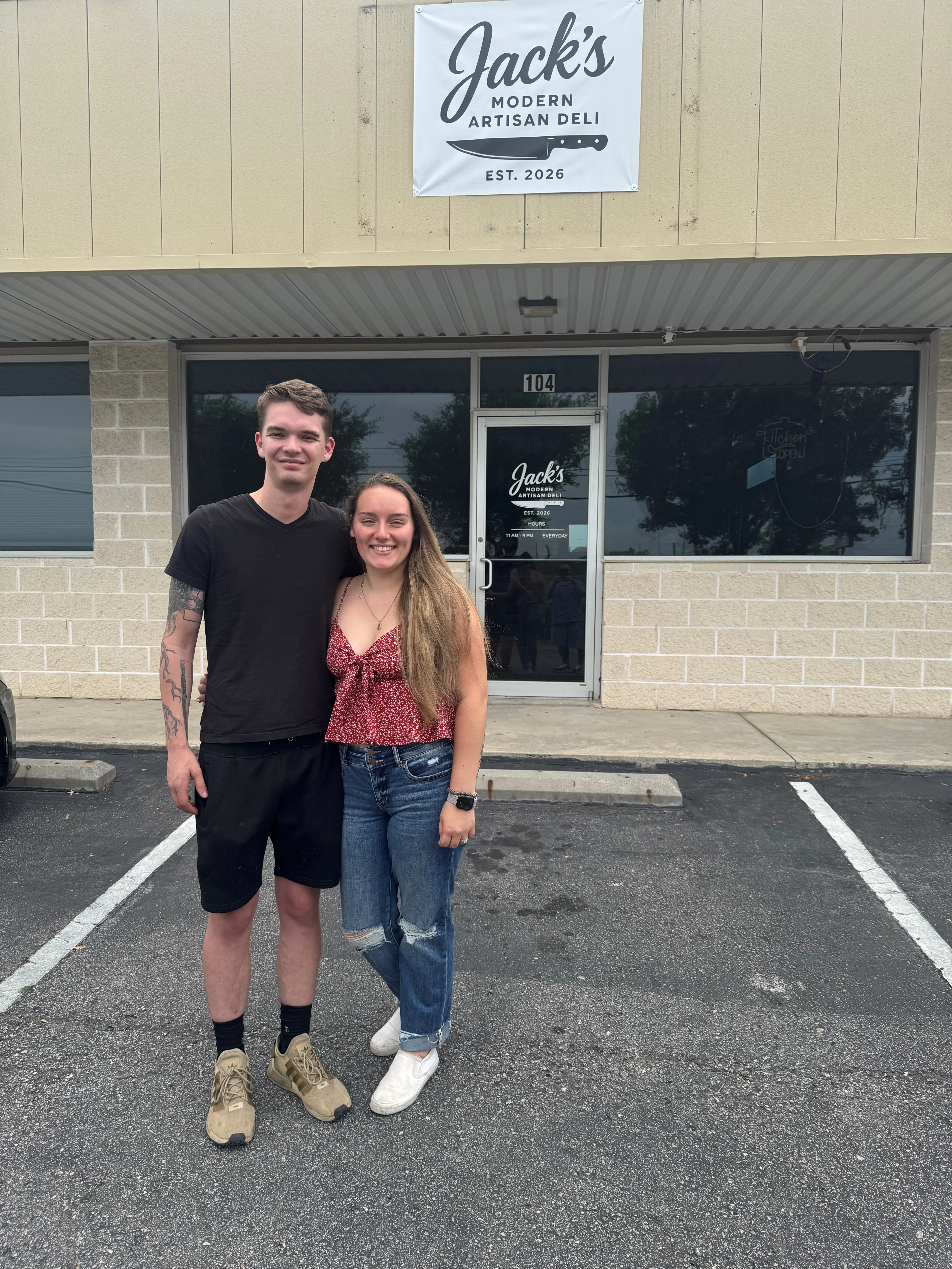 Exterior of Jack's Modern Artisan Deli with two smiling patrons