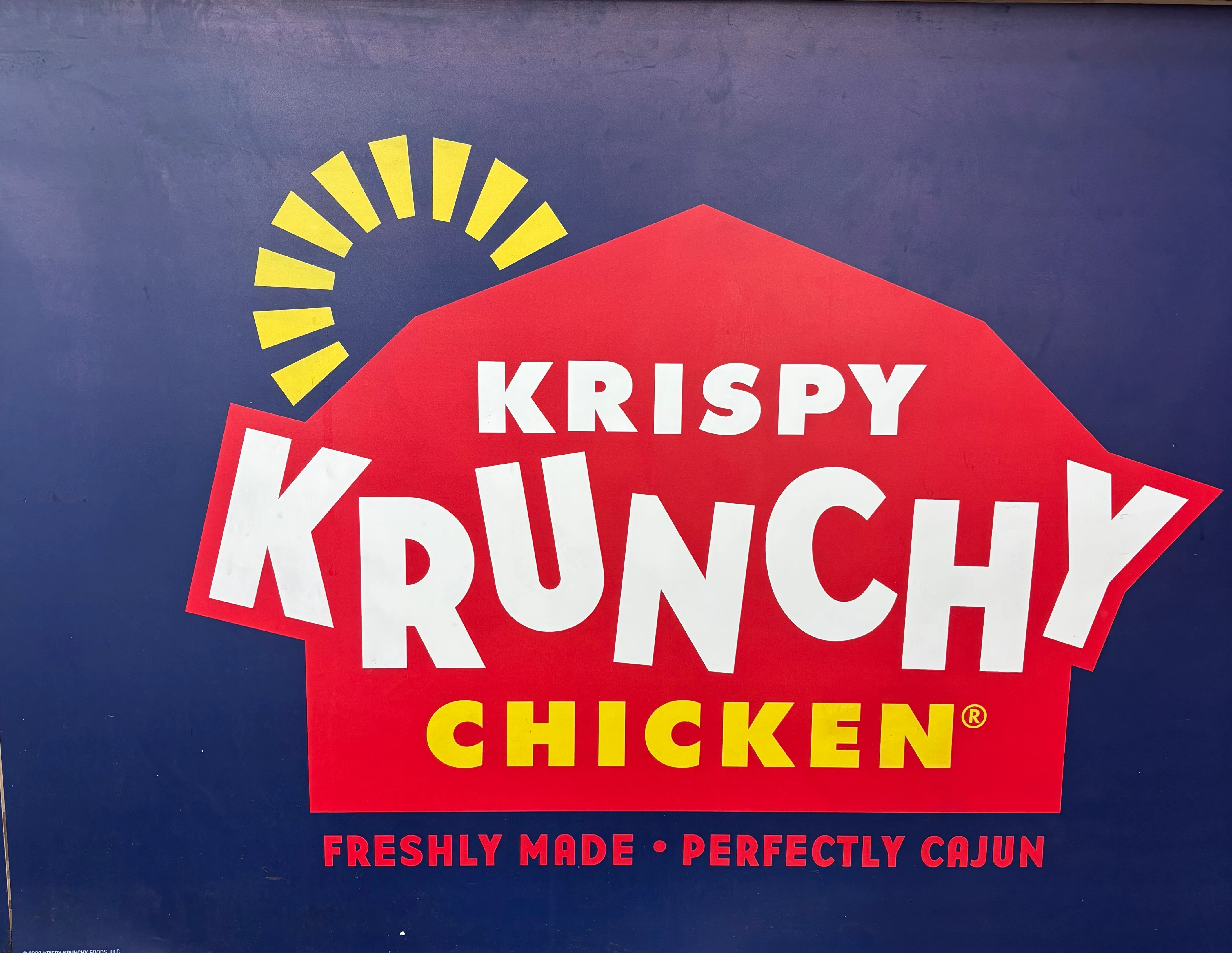 A colorful sign displaying the name of a chicken restaurant with a bold logo and tagline emphasizing its Cajun flavor.